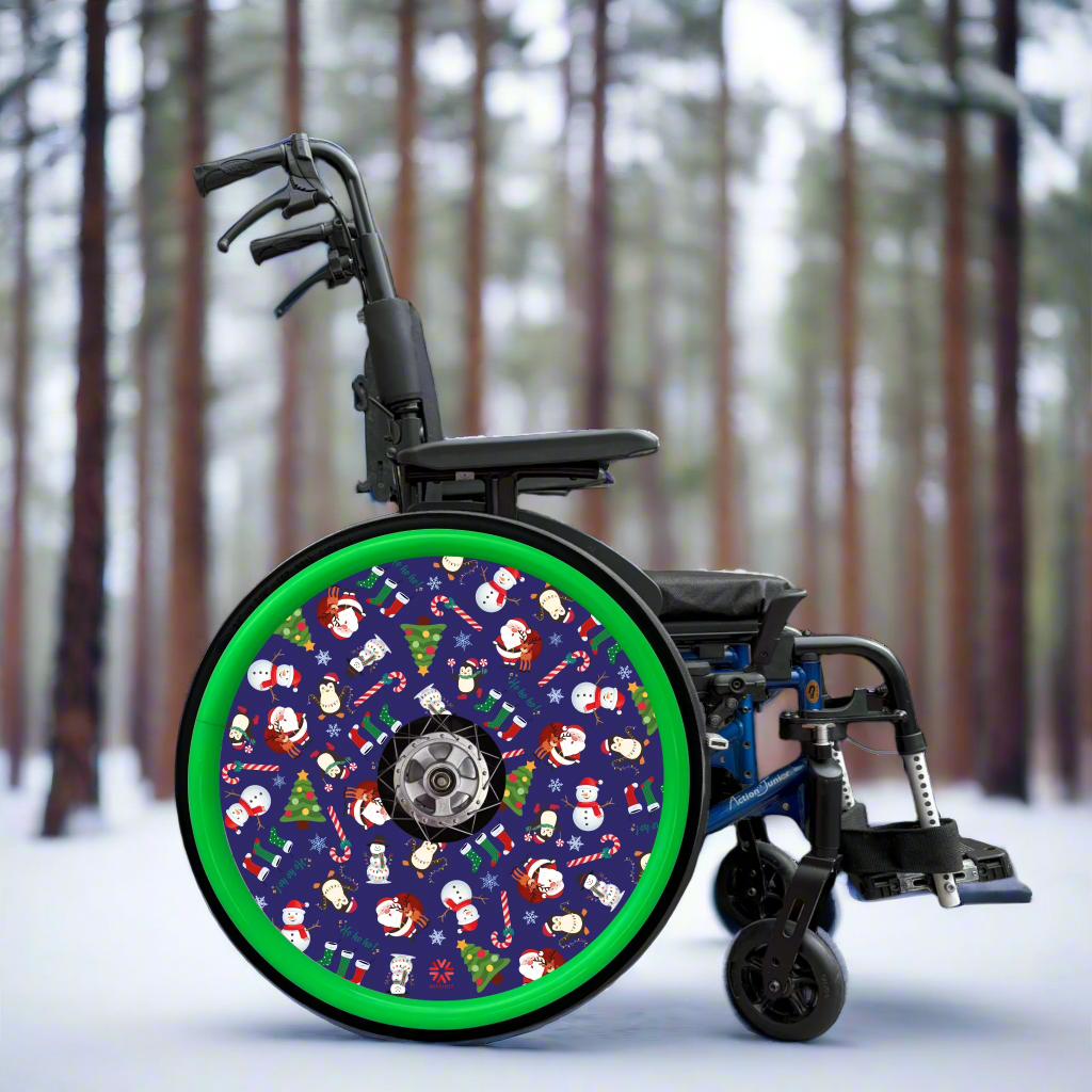 Wheelchair with spoke cover featuring Christmas-themed cartoon pattern on a blue background with green hand rim cover. Set in pine forest.