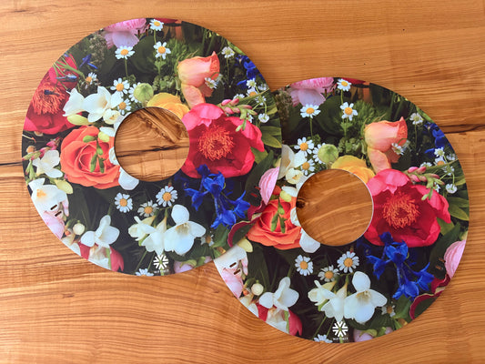 Pair of reversible NIFTIKIT Wheelchair Spoke Guards with floral and panda designs on a wooden surface.