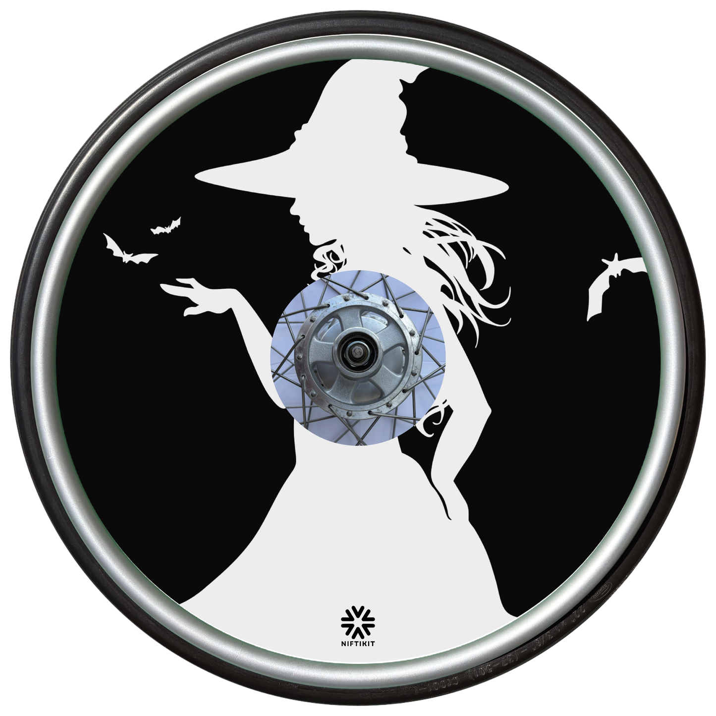 Wheelchair wheel cover on a wheel featuring the white silhouette of a witch and bats on a black background.
