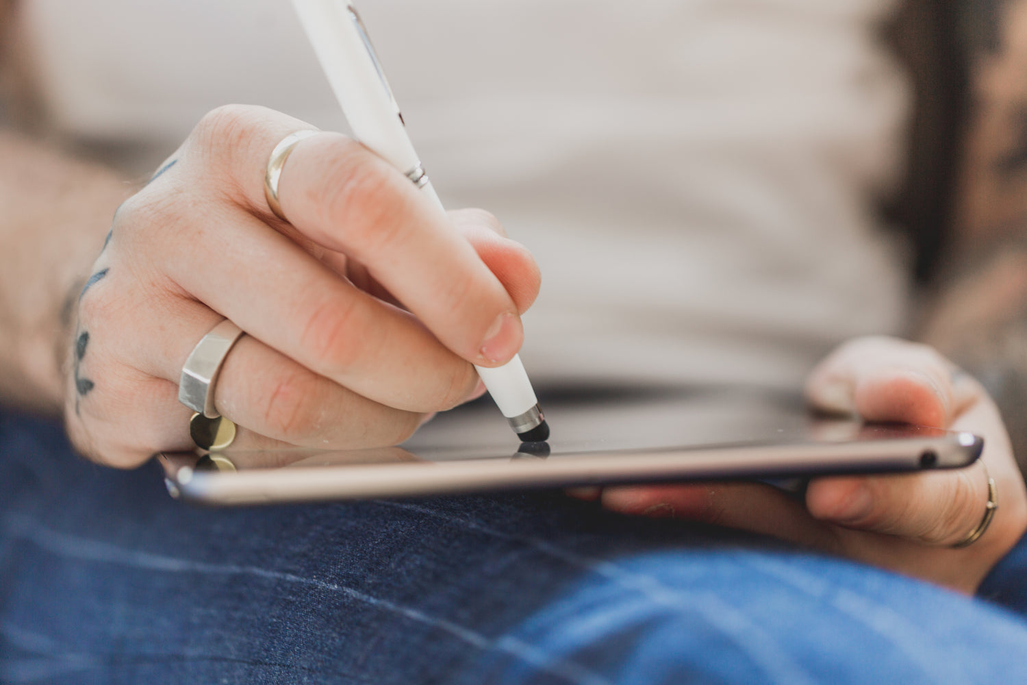Hand holding a stylus pen writing on a tablet
