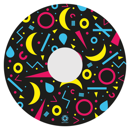 Spoke guard disc with rings, lines  and moons patterns in pink, blue, yellow. Centre hub cutout, small Niftikit label. Black background. 