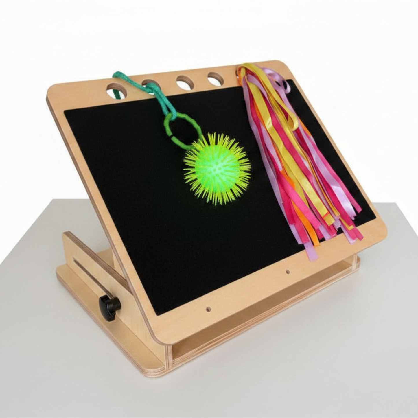 Accessible slope for visually impaired with hanging loops for toy mounting .Frame holds ball and ribbons. 