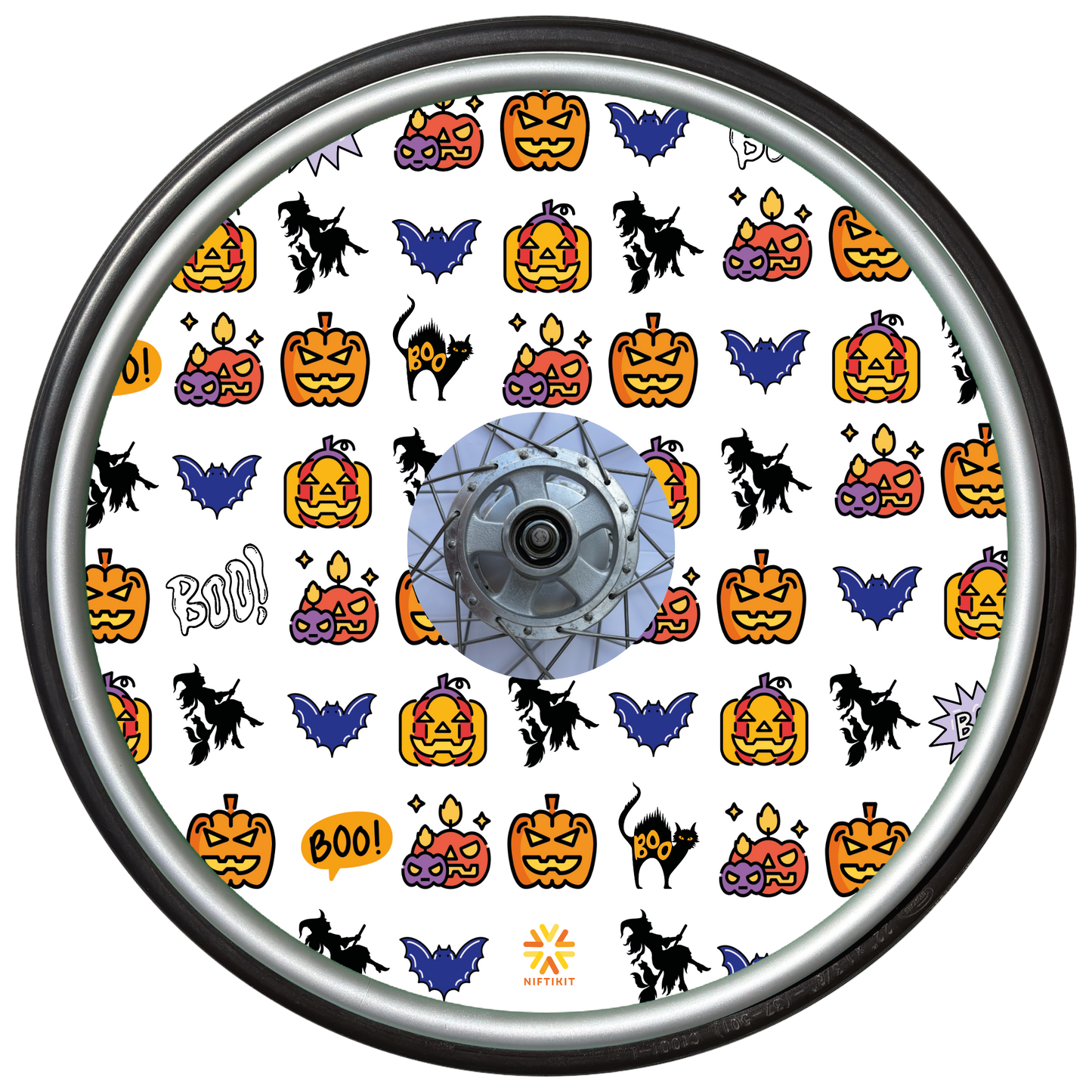 Wheelchair wheel cover on a wheel featuring pumpkins, bats, witches and Boo! on a white background.