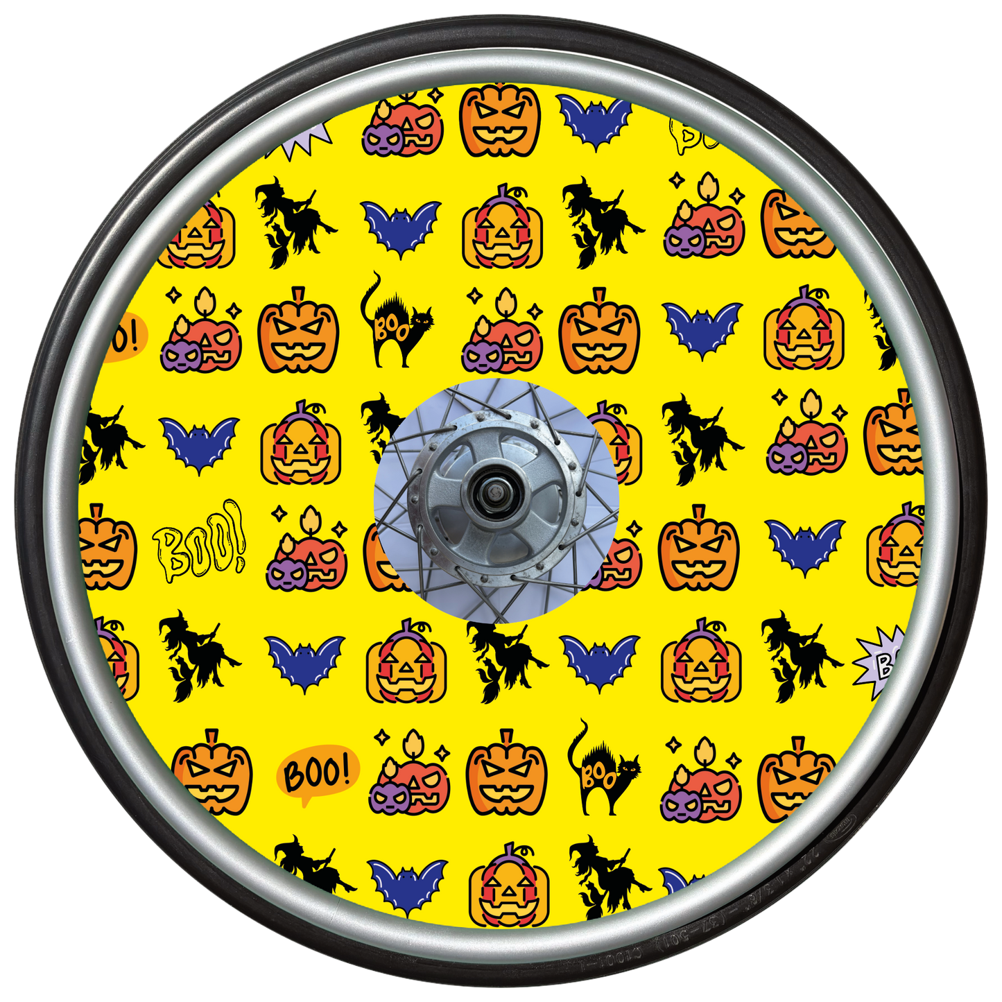 Wheelchair wheel cover on a wheel featuring pumpkins, bats, witches and Boo! on a yellow background.
