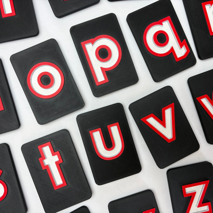 Black letter tiles with raised red and white letters . Traceable CVI friendly high contrast alphabet tiles