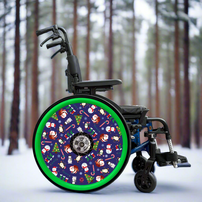 Wheelchair with spoke cover featuring Christmas-themed cartoon  pattern on a blue background with green hand rim cover. Set in pine forest. 