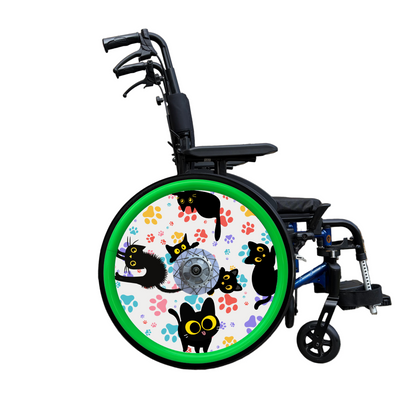 Wheelchair wheel cover on a wheelchair wit green pushrim covers. Wheel cover features black cats with orange eyes and colourful paw prints on a white background.
