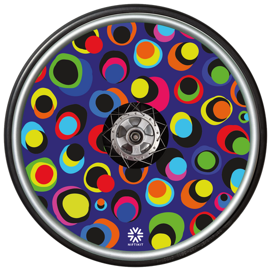 Wheelchair wheel with colourful dot pattern spoke guard covers in bright multicolour circles on a dark blue background, Niftikit Gone Dotty design