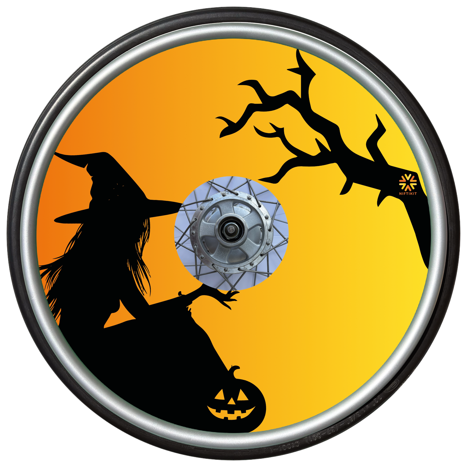 Wheelchair wheel cover on a wheel with the silhouette of a witch and tree on an orange background