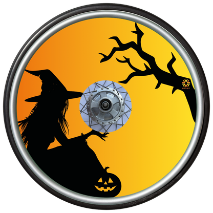 Wheelchair wheel cover on a wheel with the silhouette of a witch and tree on an orange background