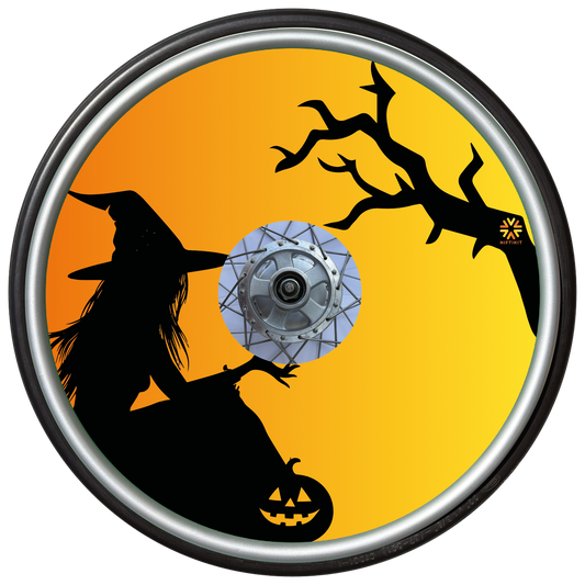 Wheelchair wheel cover on a wheel with the silhouette of a witch and tree on an orange background