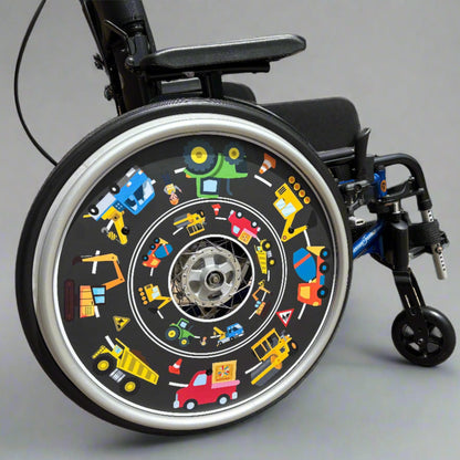 Wheelchair with a decorative wheel cover featuring colorful building site vehicle illustrations on a gray background