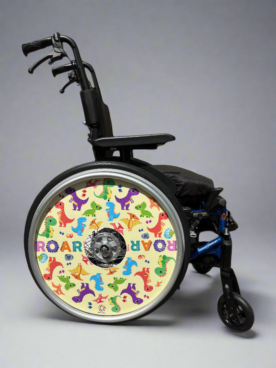 Wheelchair with a colorful wheel cover featuring dinosaur designs and cream background with the word 'ROAR'.