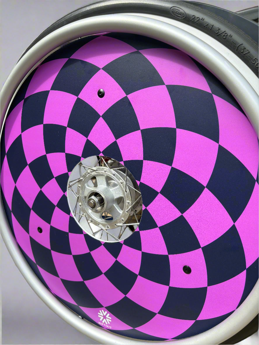 Wheelchair wheel with spoke cover with navy and purple diamonds  pattern, 3 black rivets and small white Niftikit logo. 