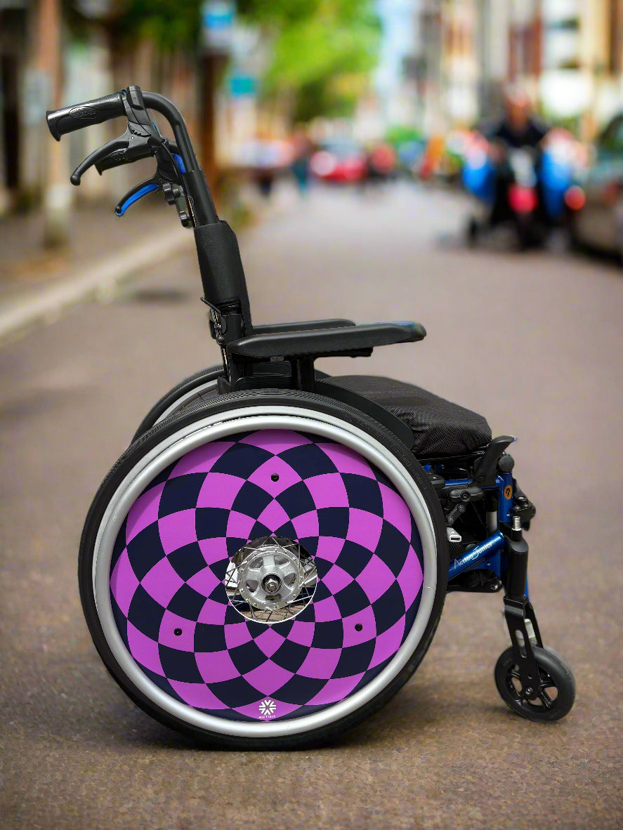 Wheelchair with navy and purple diamonds pattern wheel cover and small white Niftikit logo in a blurred street background. 