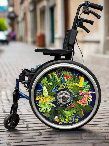 Wheelchair with wheel cover featuring colourful jungle themed animals on various shaped leaves over a navy blue background, against a blurred street backdrop.  