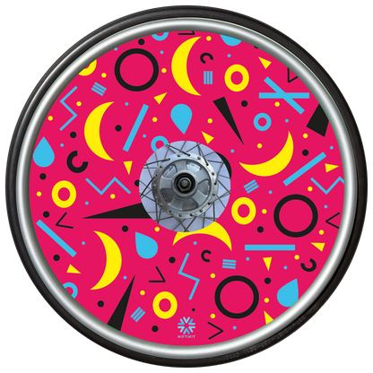 Wheelchair wheel cover with rings, lines  and moons patterns in black, blue, yellow. Centre hub cutout, small Niftikit label. Pink background. 