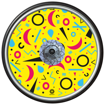 Wheelchair wheel cover with rings, lines  and moons patterns in pink, blue, black. Centre hub cutout, small Niftikit label. Yellow background. 