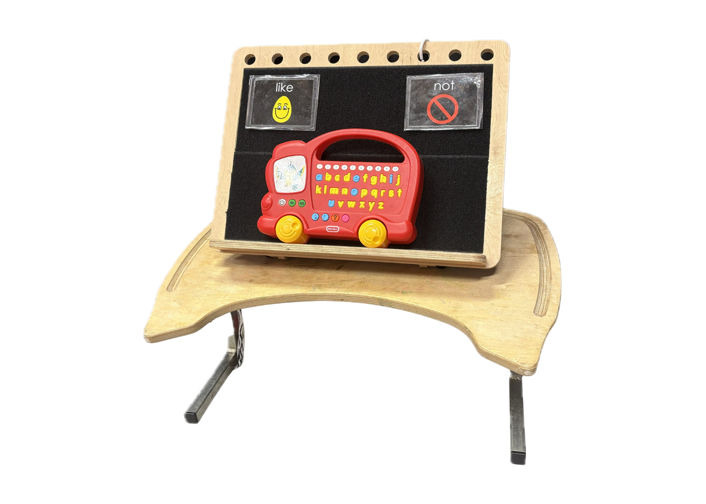 Niftikit desk frame affixed to a low tray table. The desk frame holds 2 PCS symbols of like and not and a red and yellow toy bus with the alphabet on buttons.  