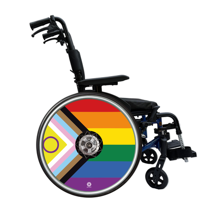 Progress Pride Flag wheelchair wheel cover fitted to a manual wheelchair wheel, colourful LGBTQ+ wheelchair accessory handmade in the UK by Niftikit.