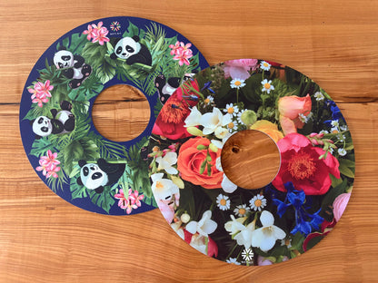 Pair of NIFTIKIT Wheelchair Spoke Guards with floral and panda designs on a wooden surface.