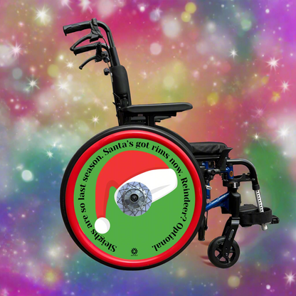 Wheelchair with wheel cover featuring a Santa hat and humorous text on a green background. Chair 