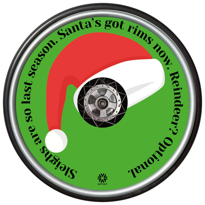 Wheelchair wheel with a Santa hat spoke guard cover and humorous text on a green background