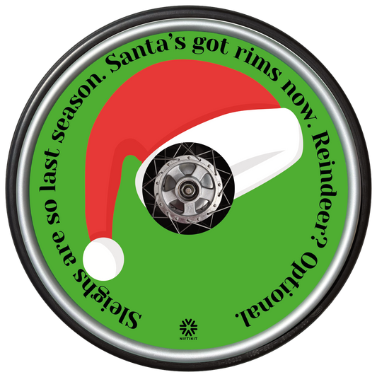 Wheelchair wheel with a Santa hat spoke guard cover and humorous text on a green background