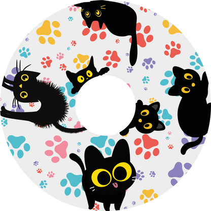 Wheelchair wheel cover featuring black cats with orange eyes and colourful paw prints on a white background.