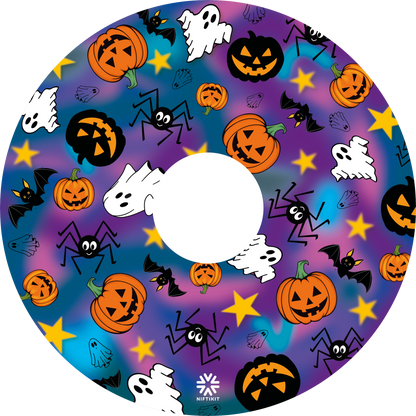 A wheelchair wheel cover or disc with centre cut out, featuring a colorful Halloween pattern with pumpkins, ghosts, bats, spiders, and stars on a purple and blue gradient background. 