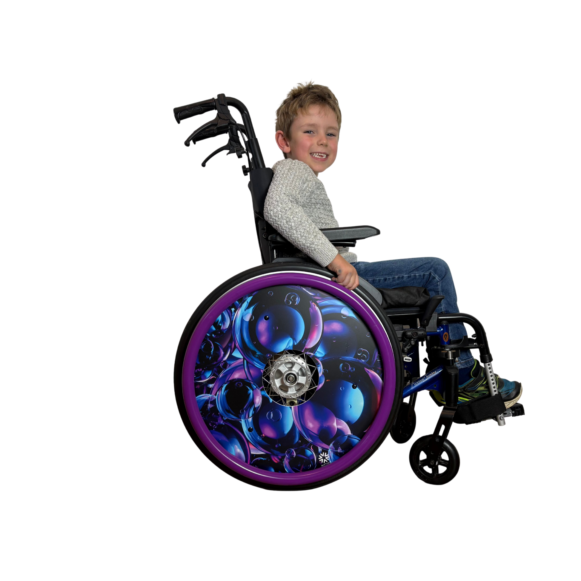 Child in wheelchair with spoke guard  featuring pueple/navy geometric design finished with a bright purple silicone push rim cover for grip and comfort.