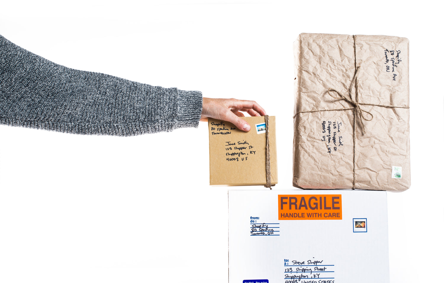 hand placing package on top of two other packages on a white background