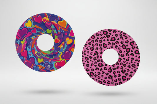 Reversible spoke guards side one shows pink, blue, purple, green, yellow hearts swirling against a purple blue background with Niftikit logo. Side 2 pink and black leopard print design