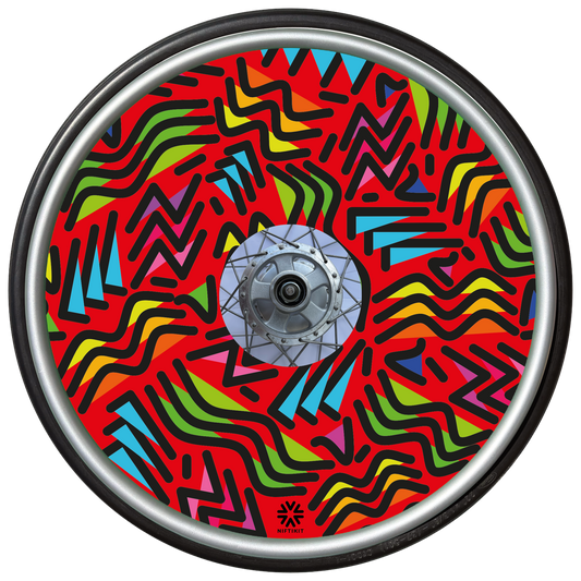 Wheelchair wheel with spoke guard featuring geometric lines of varying shapes and lengths on a red background 